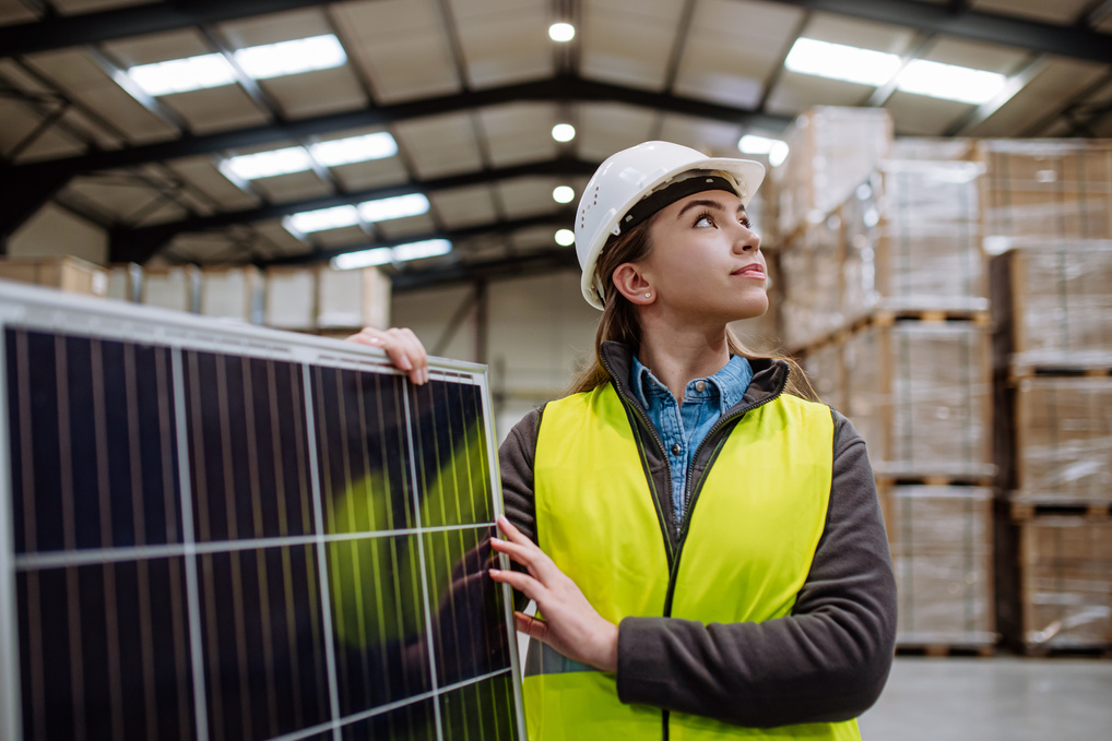 Female Worker Carrying Solar Panel in Warehouse, Factory. Solar Panel Manufacturer, Solar Manufacturing.
